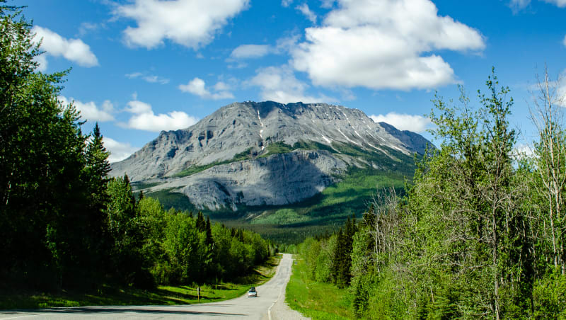 road leading to the base of a large mountain with many folds present