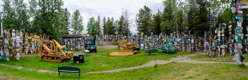 panorama of sign post forest with some historic heavy machinery on display