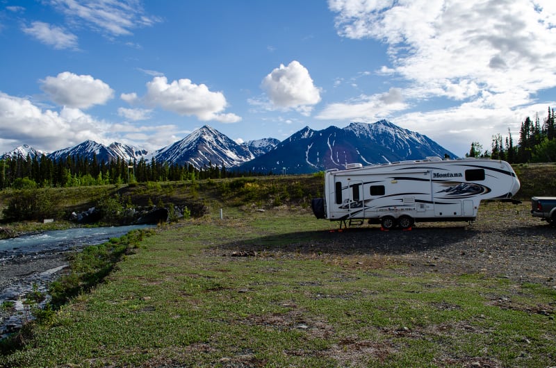 our rv with mountains in the background and a creek running along side