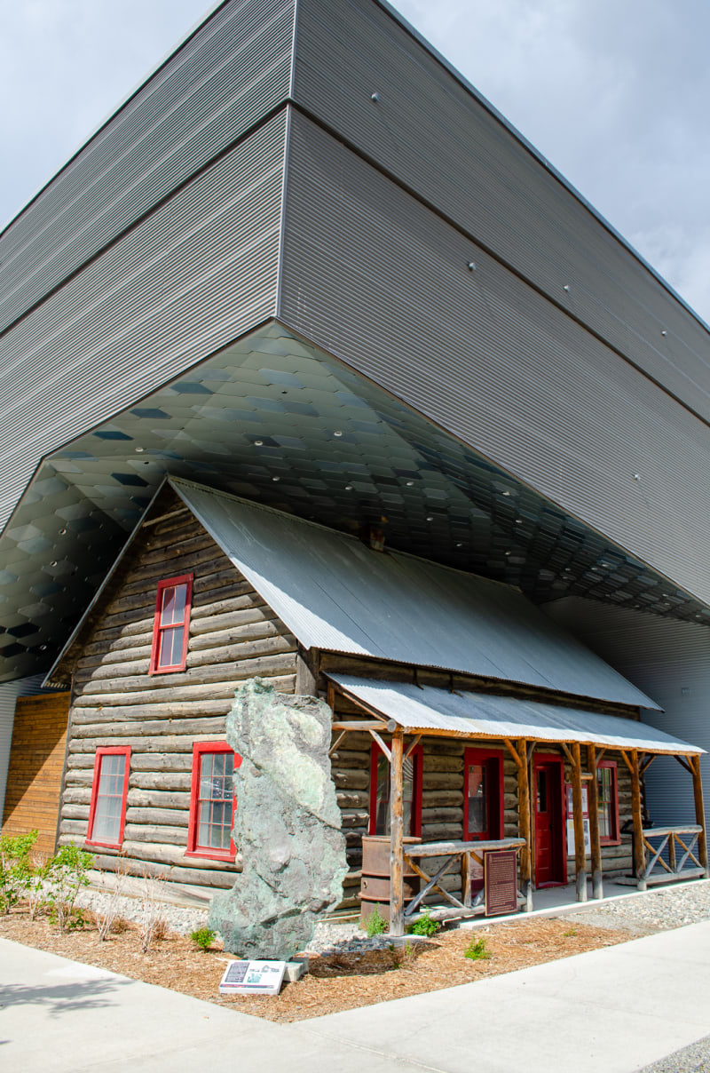 large modern structure wrapping over and around an old log cabin