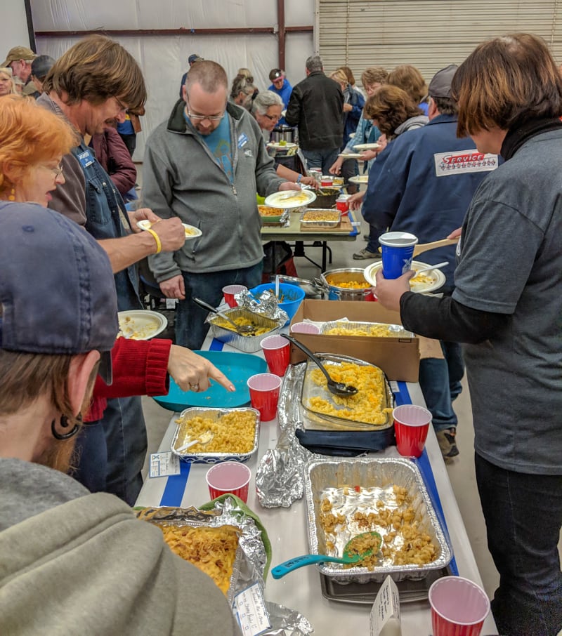 people around tables filled with mac and cheese