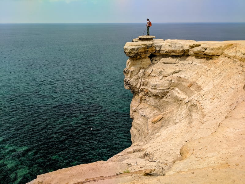 sushila standing on the edge of a cliff looking at the water