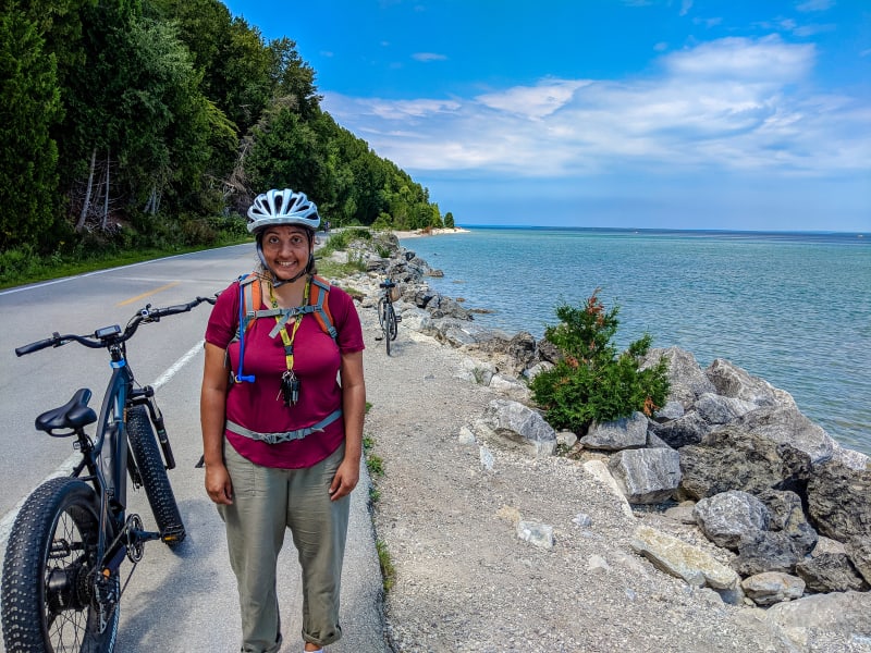 sushila posing with her bike along the shoreline road