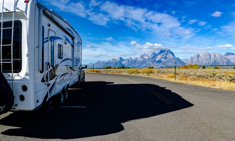 the truck and rv with the teton mountains in the background