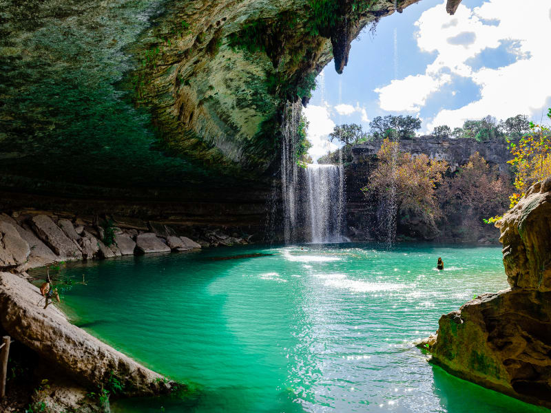 sushila swimming under a rock cliff at hamilton pool preserve