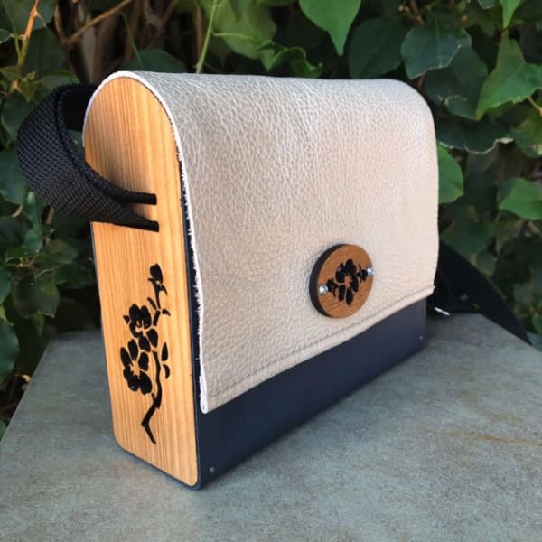 Laser cut wood and leather bag-handcrafted from upcycled materials. Adjustable  woven strap allows these gorgeous bag to be worn cross body or as a shoulder bag. Exterior measures 7 inches x 6 1/4 inches tall by 2 3/8 inches. More styles and color combos available on web site.