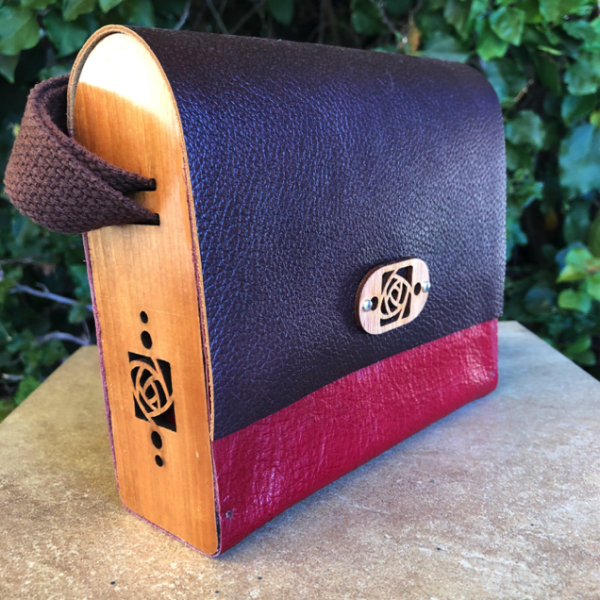 Laser cut wood and leather bag-handcrafted from upcycled materials. Adjustable  woven strap allows these gorgeous bag to be worn cross body or as a shoulder bag. Exterior measures 7 inches x 6 1/4 inches tall by 2 3/8 inches. More styles and color combos available on web site.