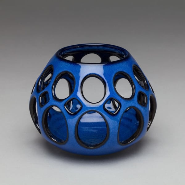 Inspired by midcentury modern design, this tealight holder is wheel thrown and hand pierced stoneware with a vibrant blue glaze that breaks to black at the edges. Small holes are created when the clay is still wet and then each hole is painstakingly enlarged and smoothed when the clay is bone dry. Gem-like sculpture is lovely as an accent piece, or is stunning as a centerpiece with a candle inside. Use it to light up any indoor or outdoor space. It it fascinates and captivates throwing flickering patterns of light and shadow onto a table or nearby wall.