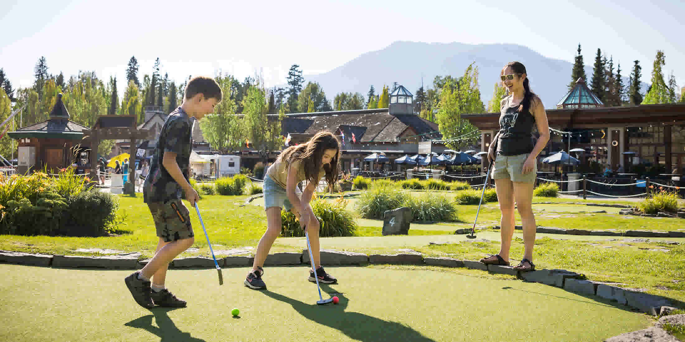 Two kids and a teen playing mini golf at the Adventure Zone in Whistler
