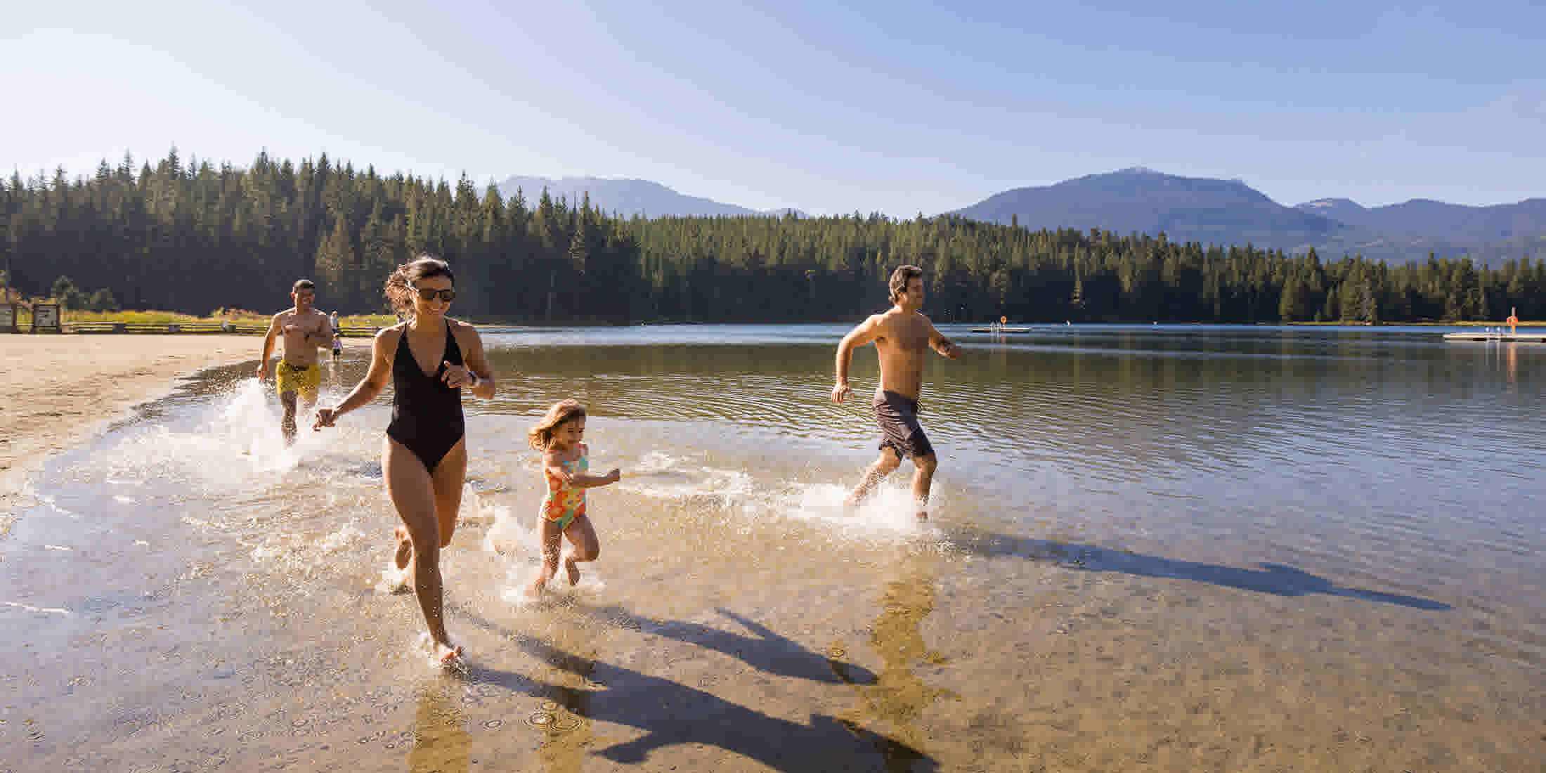 Family running into the waters of Lost Lake in Whistler BC