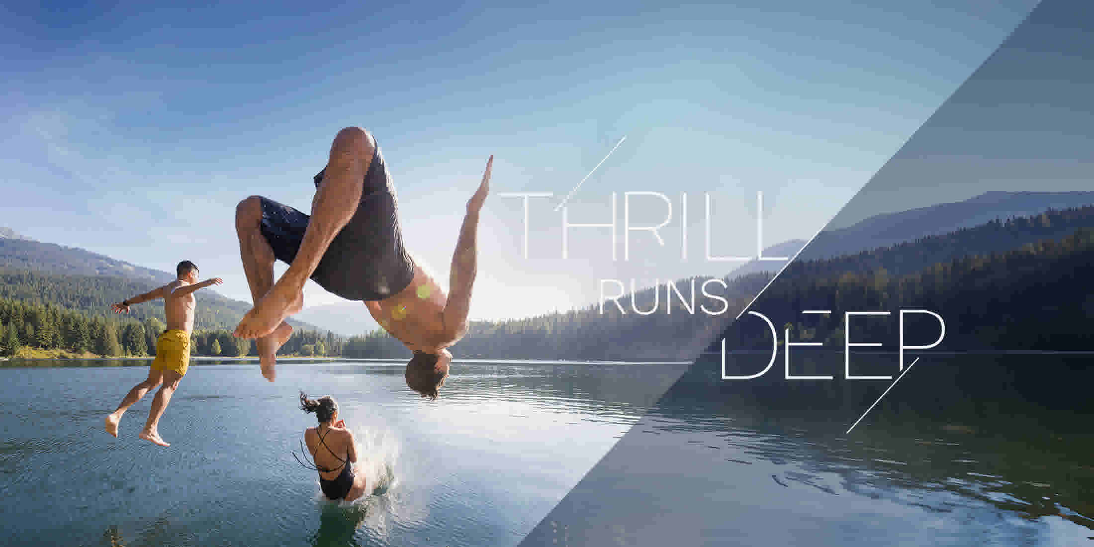 People jumping off a dock into a Whistler lake on a sunny summer day