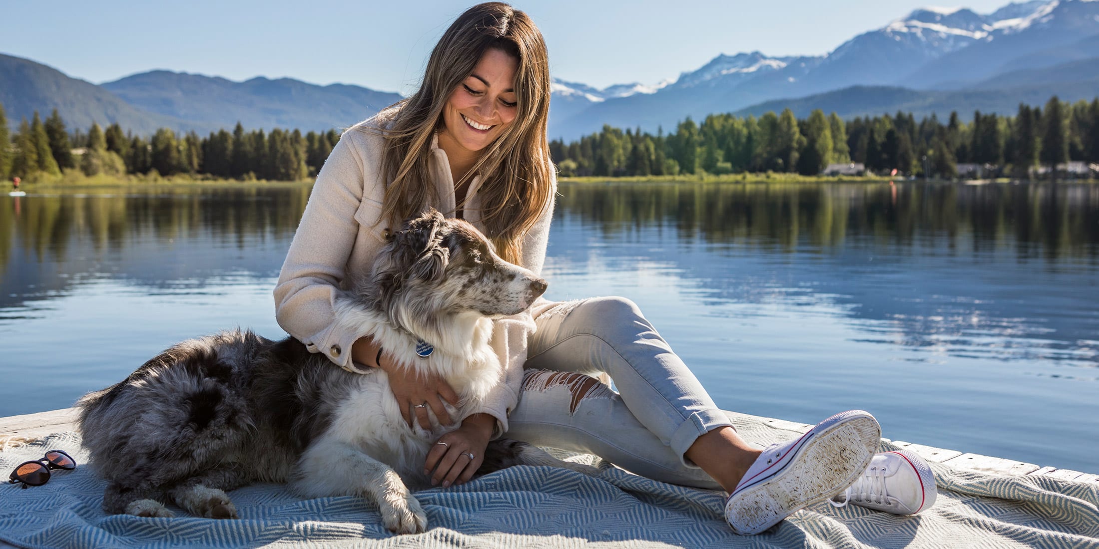 A person sitting with their dog on a dock on Alta Lake in Whistler, British Columbia