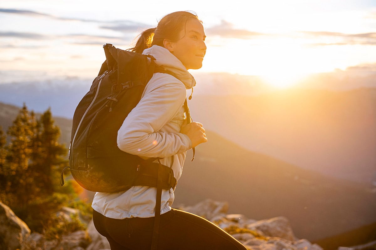 Hiker with a backpack enjoying sunset views over Whistler’s alpine landscape, surrounded by mountain peaks and golden light.