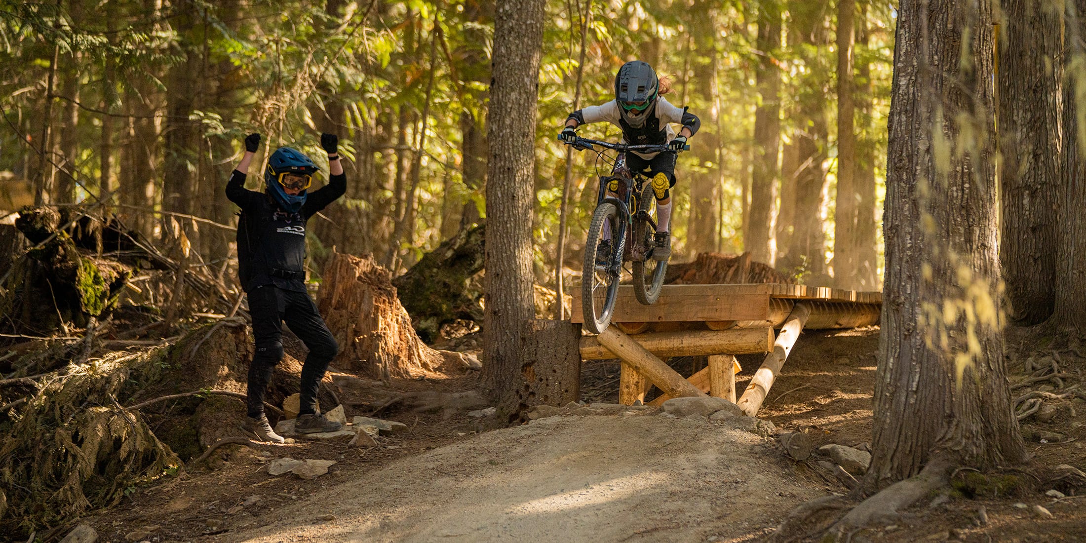 Bike instructor cheers on a person riding a drop in the Whistler Bike Park
