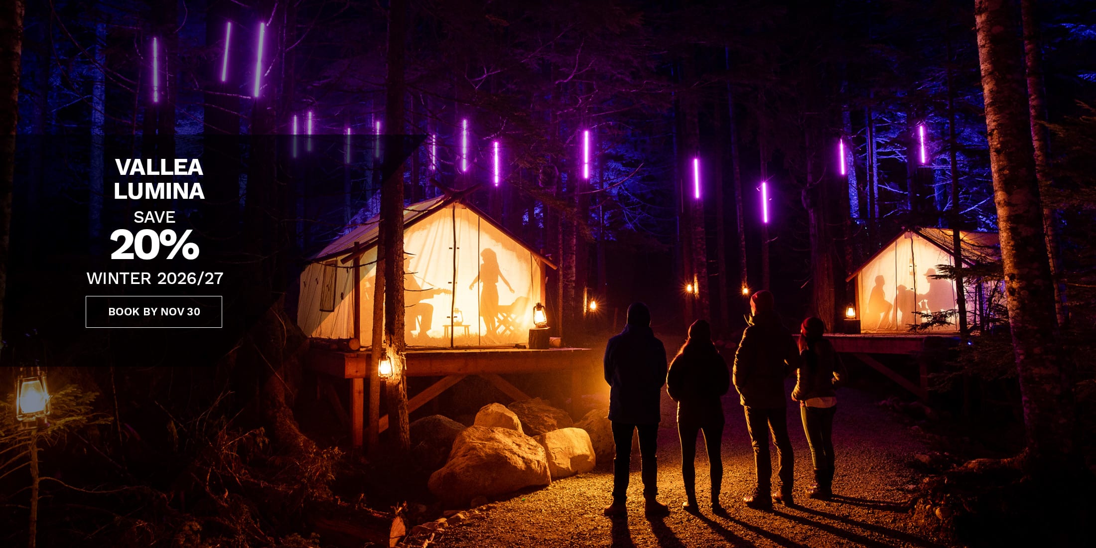 Vallea Lumina winter offer in Whistler, with visitors exploring an illuminated forest experience of glowing cabins and colourful lights. Save 20% for winter 2026/27 when booked by November 30.