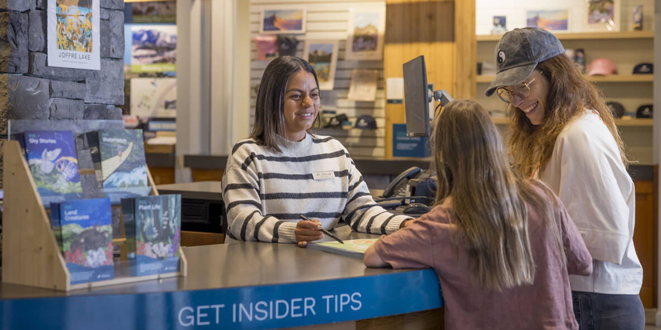 Visitor centre staff assisting a woman and child with maps and local tips.
