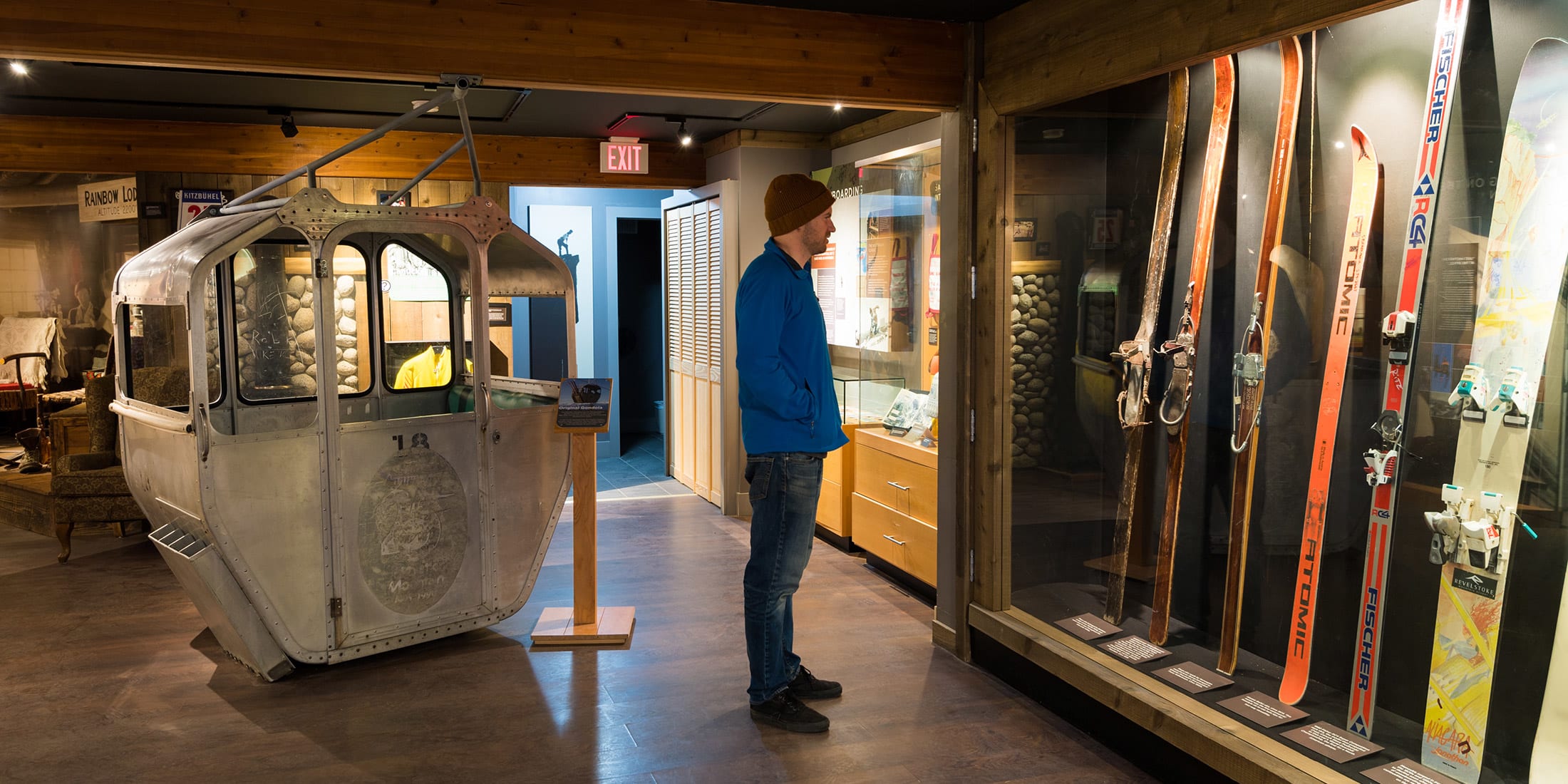 A visitor explores Whistler’s mountain culture at a heritage museum, standing beside a vintage gondola and a display of retro skis. The space blends nostalgia and alpine history, celebrating decades of adventure on snow.