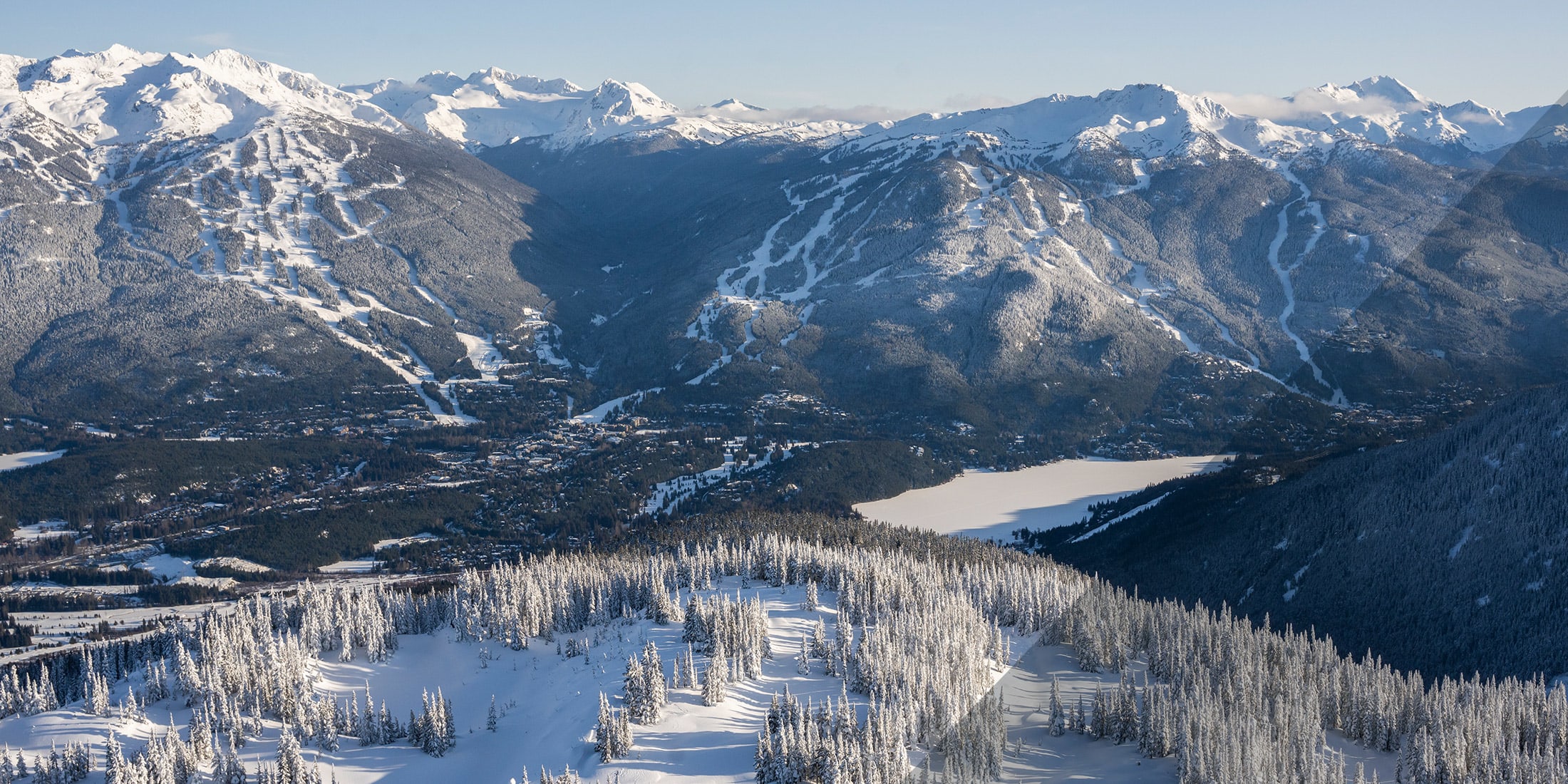 An aerial view of Whistler and Blackcomb Mountains with Whistler Valley below in the springtime.