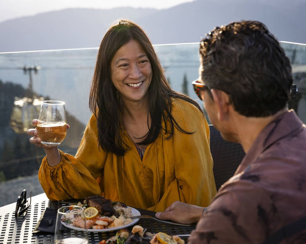 Couple enjoying sunny, mountaintop dining on the Roundhouse Lodge patio