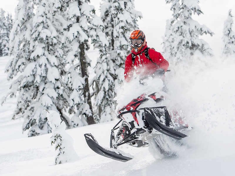 Snowmobiler crossing untouched powder beneath Whistler’s towering, sunlit alpine peaks.
