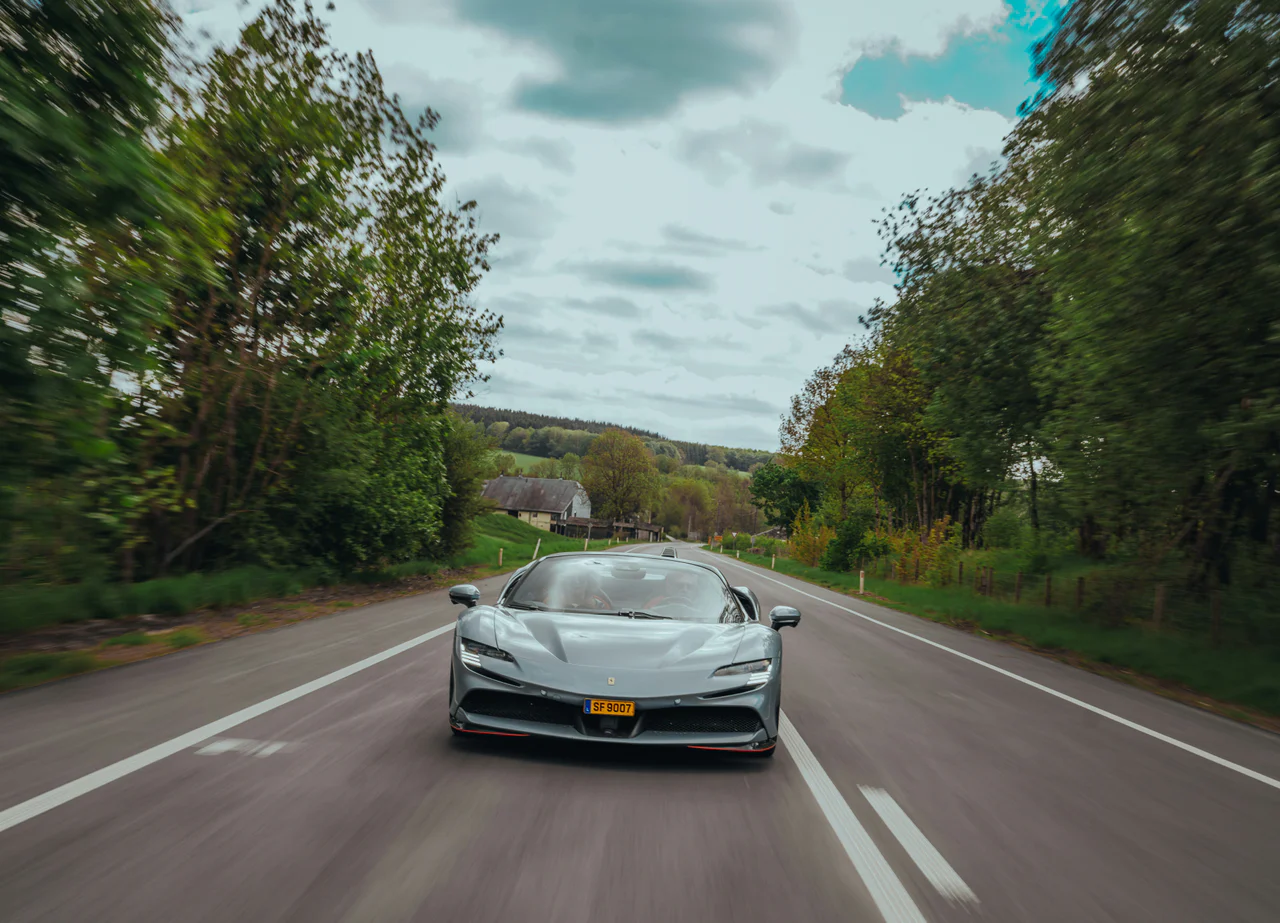 A gray ferrari speeds along a winding road.