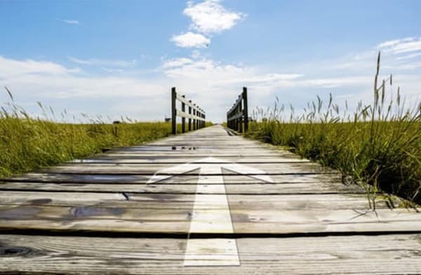 Weg mit Pfeil über eine Brücke unter blauen Himmel