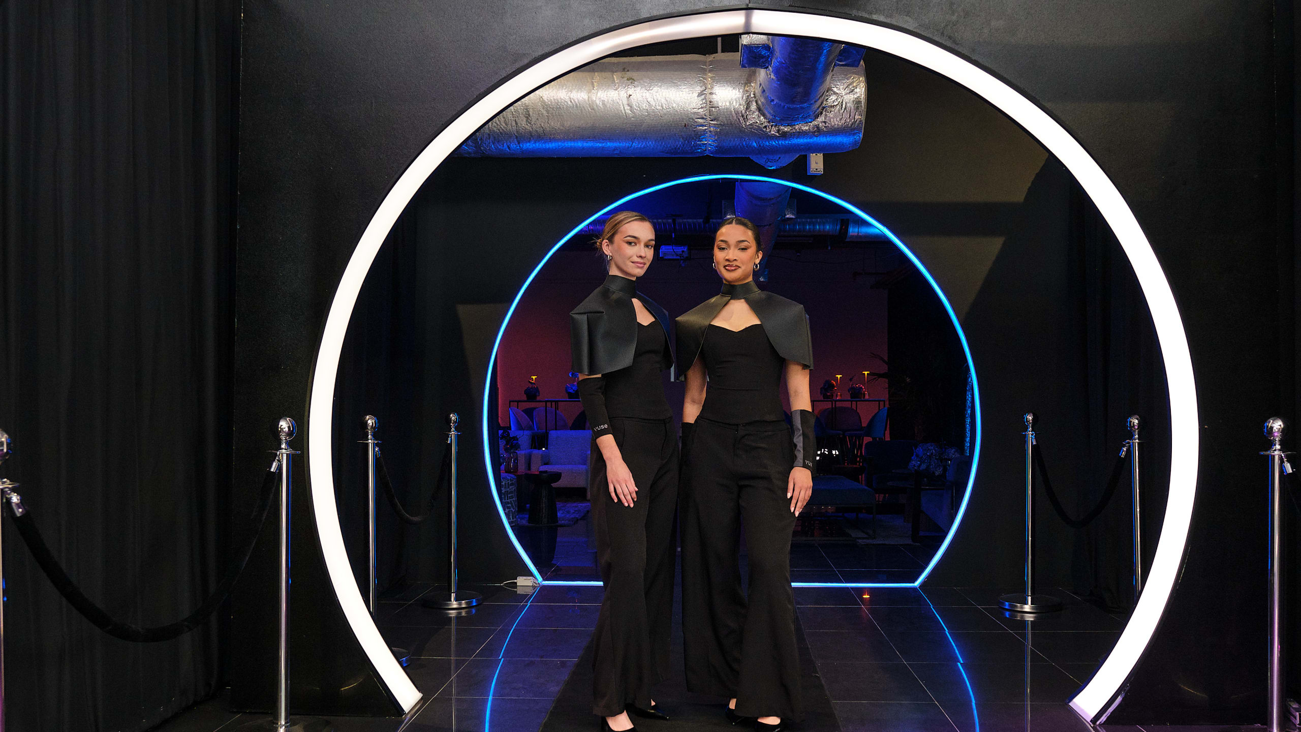 Event hosts at an illuminated arrival portal in the WiggleVerse.