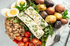 nicoise salade with pacific halibut on plate with potatoes, olives, and vegetables