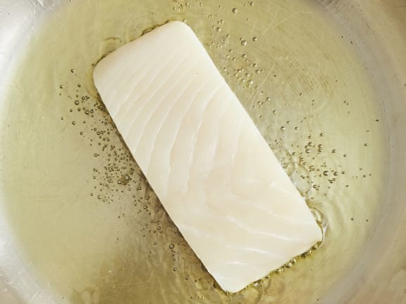 raw halibut fillet in skillet