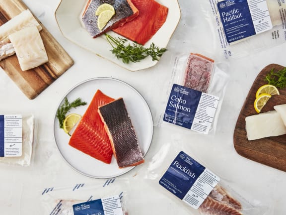 a variety of the healthiest fish to eat from wild alaskan company, with fillets of wild-caught seafood on plates and in packaging