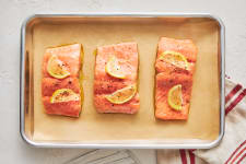 raw salmon with olive oil and seasoning on baking sheet