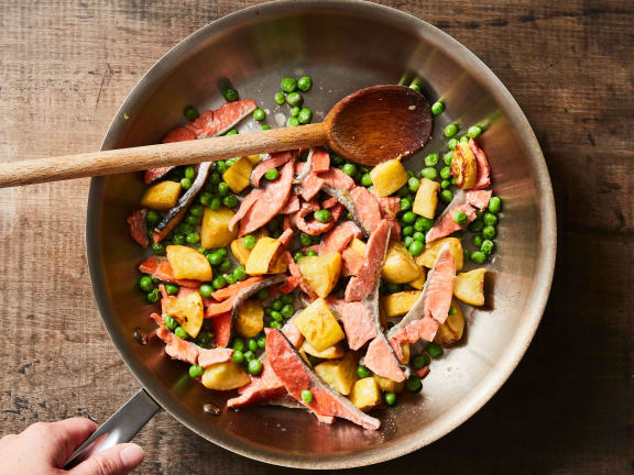 strips of sockeye salmon in a skillet with peas and summer squash