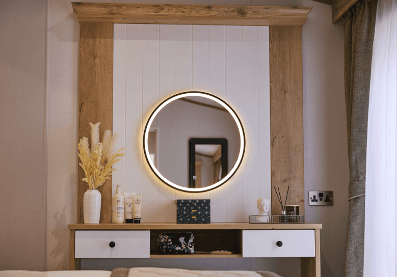 The Willerby Dorchester dressing area has an LED mirror hanging above a oak effect dressing table with white accents.