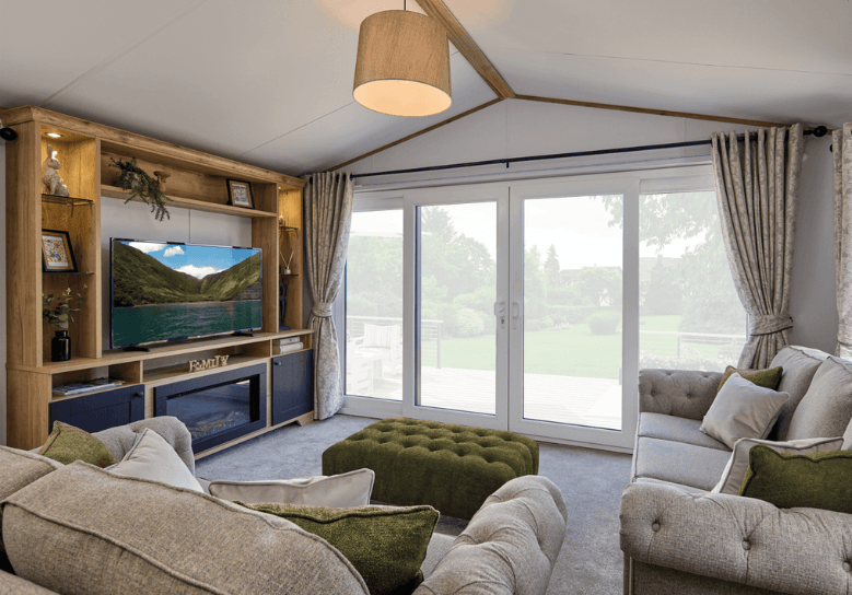 The Willerby Dorchester spacious lounge with forest green furnishings and a feature oak effect media unit.