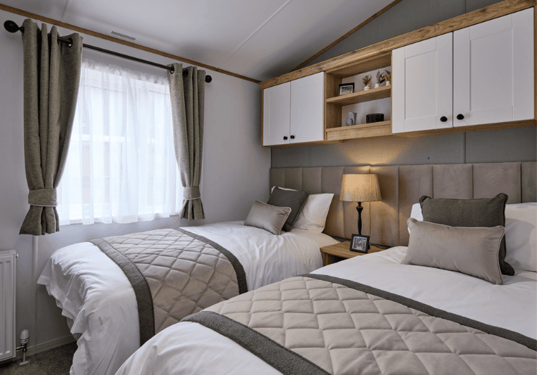 The Willerby Dorchester twin bedroom with a long grey upholstered headboard and plenty of storage for the space.