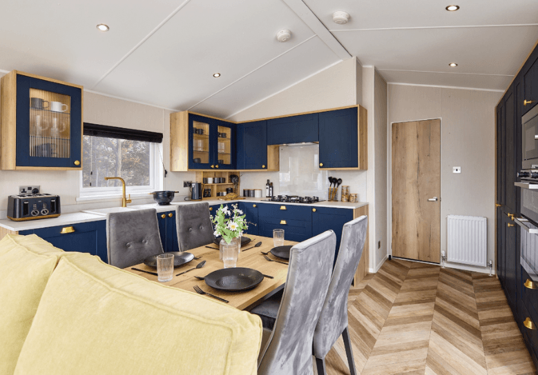 The Willerby Gainsborough contemporary kitchen with a dining oak effect table and grey chairs, and has herringbone wooden effect flooring.