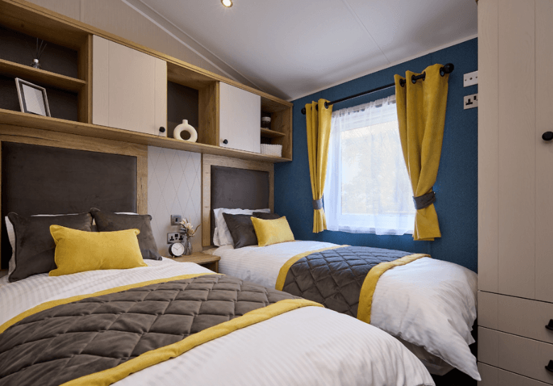 The Willerby Gainsborough twin bedroom is surrounded by storage with grey and yellow soft furnishings.