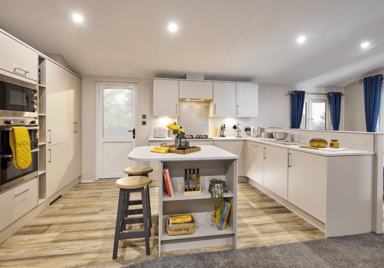 The Willerby Hayward C- shaped kitchen with white cupboards and worktops which has a kitchen island in the centre.
