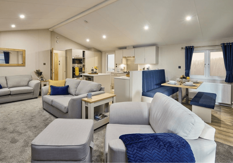 The Willerby Hayward lounge with three grey sofas with a matching footstool, and has blue soft furnishings to tie in the colour scheme.