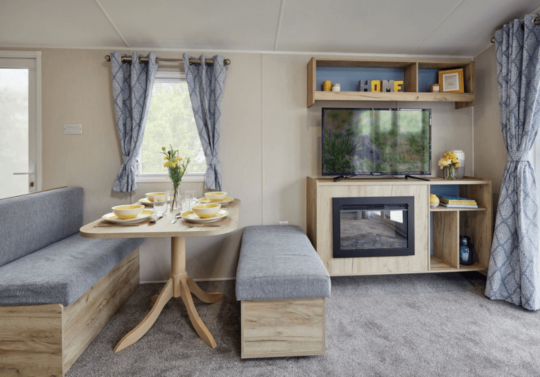 The Willerby Linwood dining area with two grey and oak effect seating and a matching oak effect table, and an oak effect media storage unit with a built in electric fire.