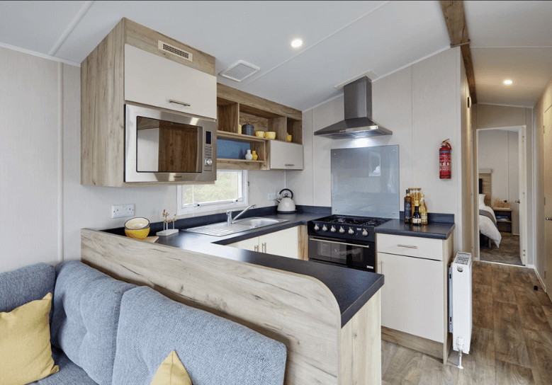 The Willerby Linwood kitchen has oak effect storage units with cream cupboard doors, and black worktops.