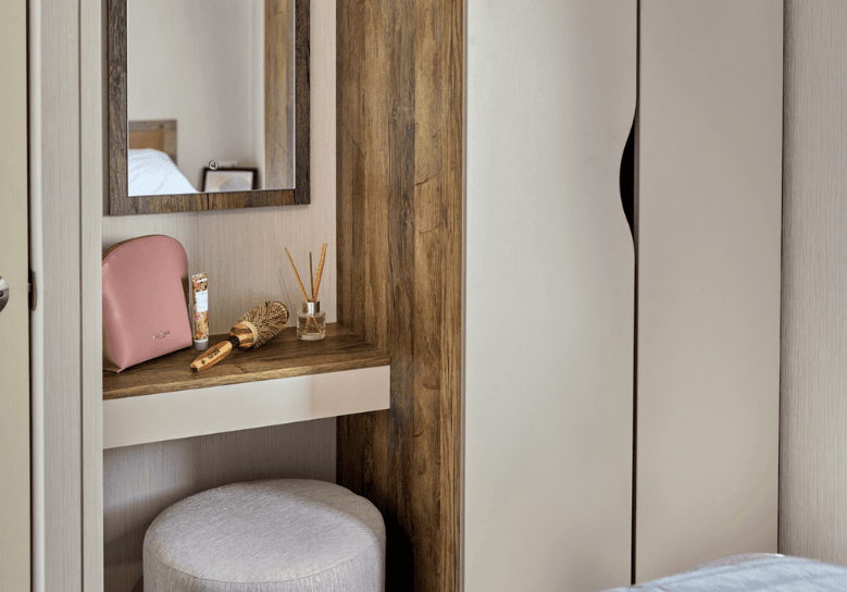 The Willerby Malton dressing area with cream wardrobe doors, oak effect units and an upholstered stool.