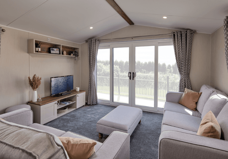 The Willerby Malton lounge has two freestanding sofas with a matching footstool, with a cream and oak effect media unit.