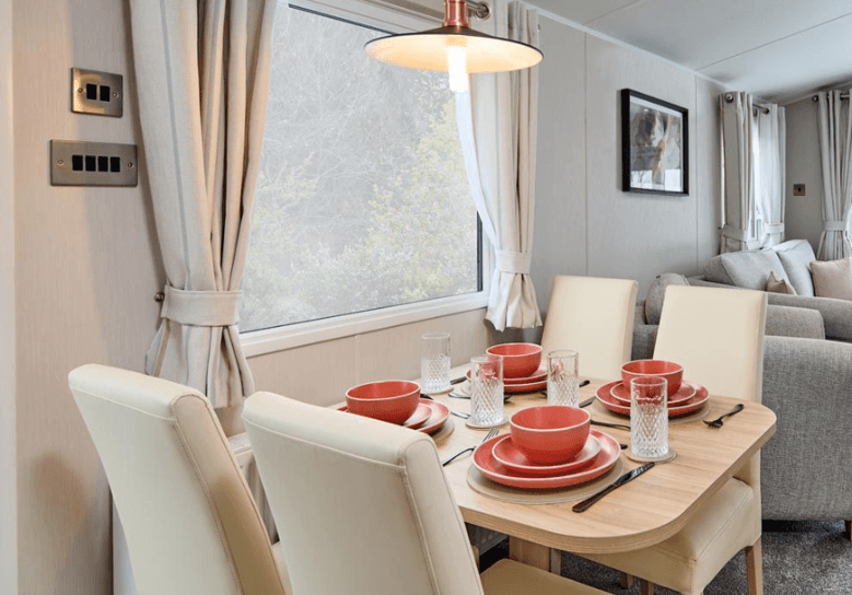 The Willerby Manor dining area has 4 cream chairs surrounding an oak effect table with a window view.