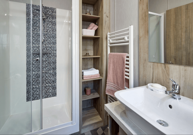 The Willerby Mapleton bathroom has oak effect storage units and a shower.