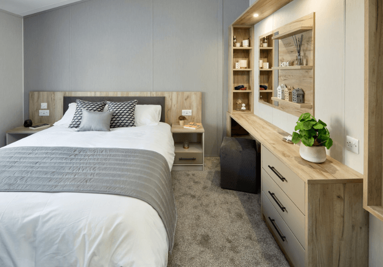 The Willerby Mapleton master bedroom has an oak effect storage dressing area with matching bedside tables.