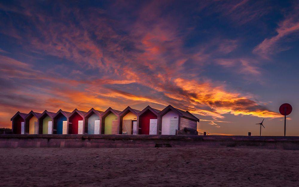 Colourful beach huts by the sea in Blyth, in front of the beautiful sun set