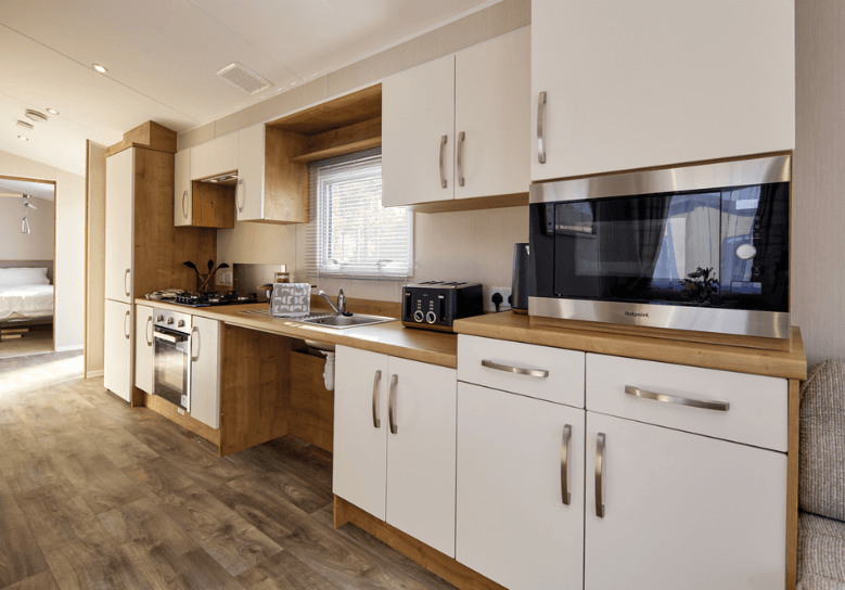 The Willerby Richmond kitchen has oak effect storage units and worktop with white cupboard doors, with space under the sink perfect for wheelchair users.