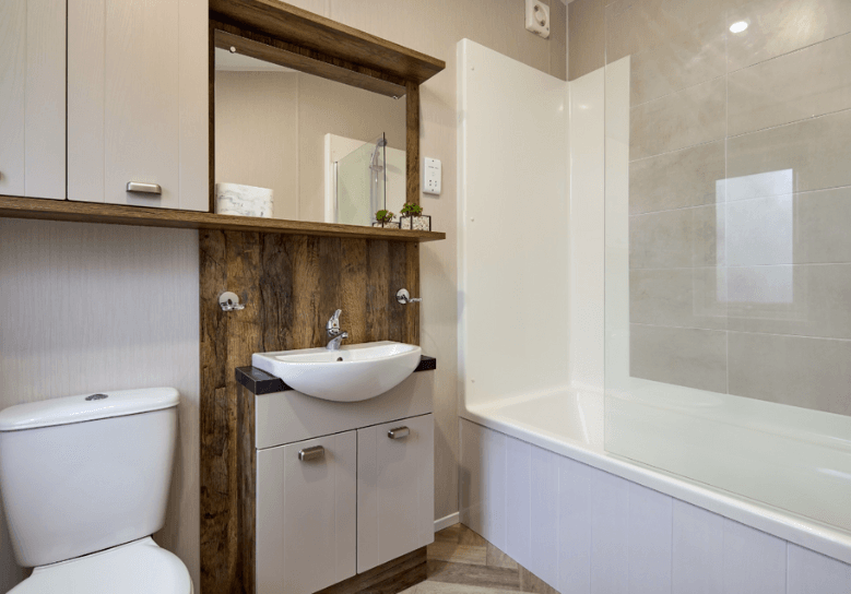 The Willerby Sheraton ensuite has dark oak effect storage units with white cupboard doors and a bathtub.