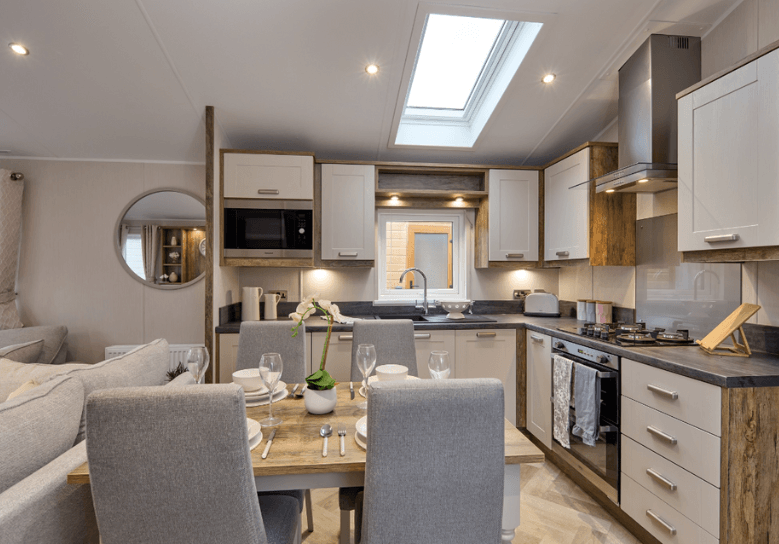 The Willerby Sheraton kitchen has oak effect storage units with white cupboard doors, and an oak effect and grey dining table in the center.